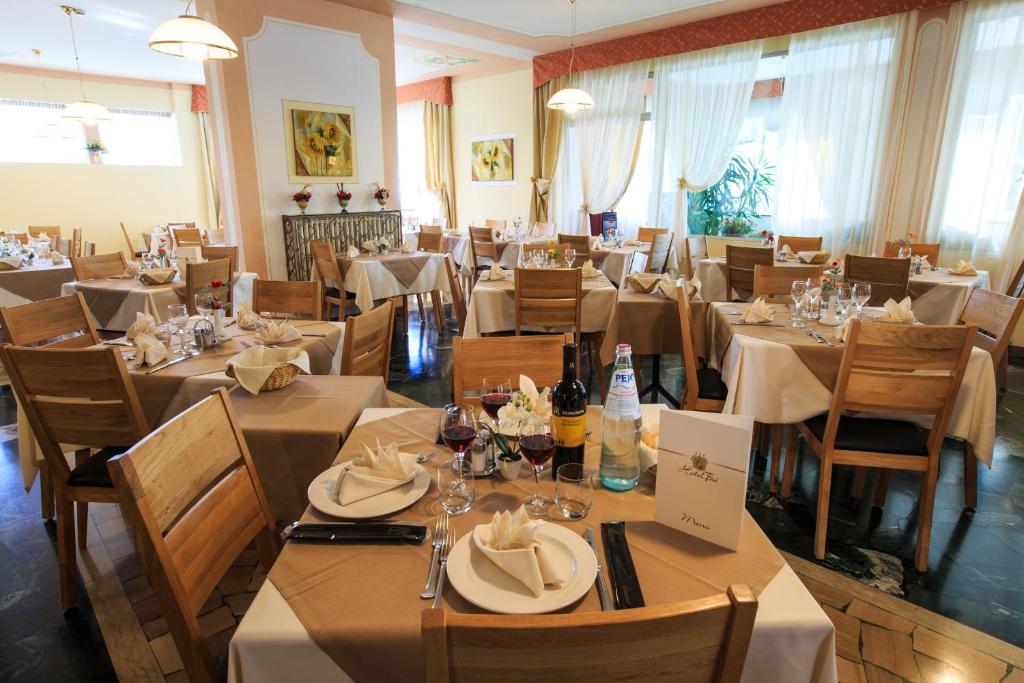 restauracja z białymi stołami i krzesłami oraz stolarką w obiekcie Hotel Fai w mieście Fai della Paganella