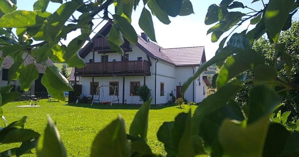 Agroturystyka "U Kasi" في Ścinawka Górna: منزل أبيض مع ساحة مع عشب أخضر