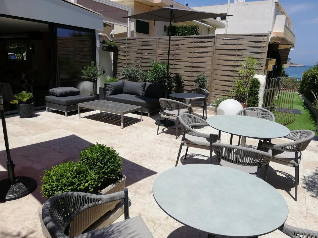 a patio with tables and chairs and a couch at Hotel Miramar- Cap d'Antibes - La Garoupe plage in Antibes