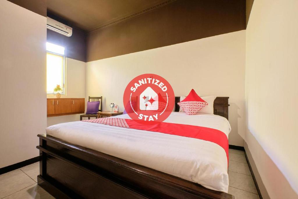 Un dormitorio con una cama con un letrero rojo. en Super OYO 2519 Mayang Garini, en Magelang