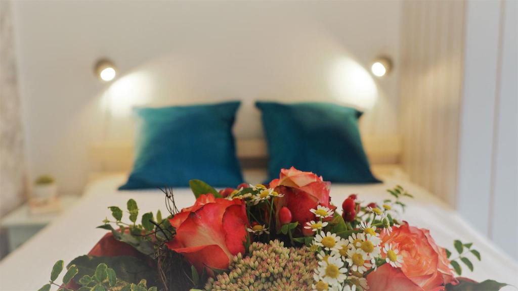 un mazzo di fiori su un letto con cuscini blu di Frida - Feines Studio mit Südterrasse a Steinkirchen