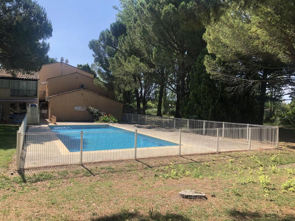 une clôture autour d'une piscine en face d'une maison dans l'établissement Appartement 238 village LES SALICORNES, à Arles