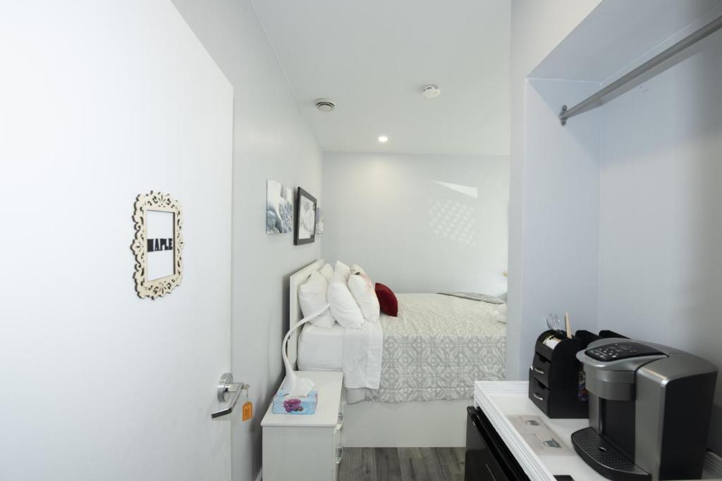a white bedroom with a bed and a tv at Serene Niagara Inn in Niagara Falls