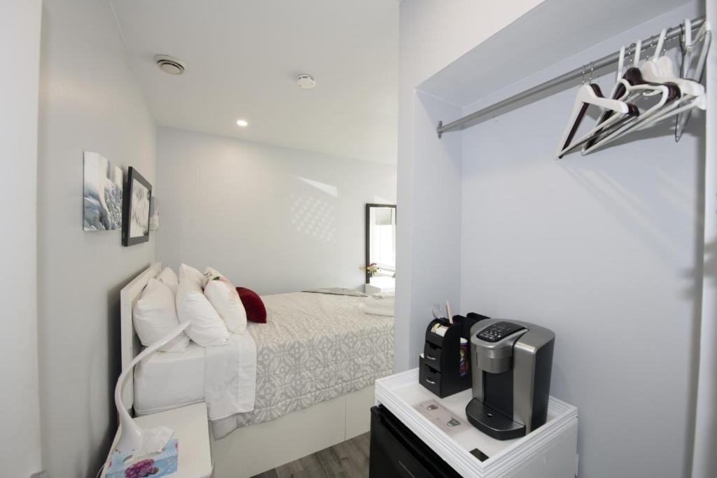 a white bedroom with a bed and a tv at Serene Niagara Inn in Niagara Falls