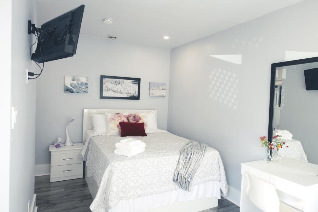 a white bedroom with a bed and a sink at Serene Niagara Inn in Niagara Falls
