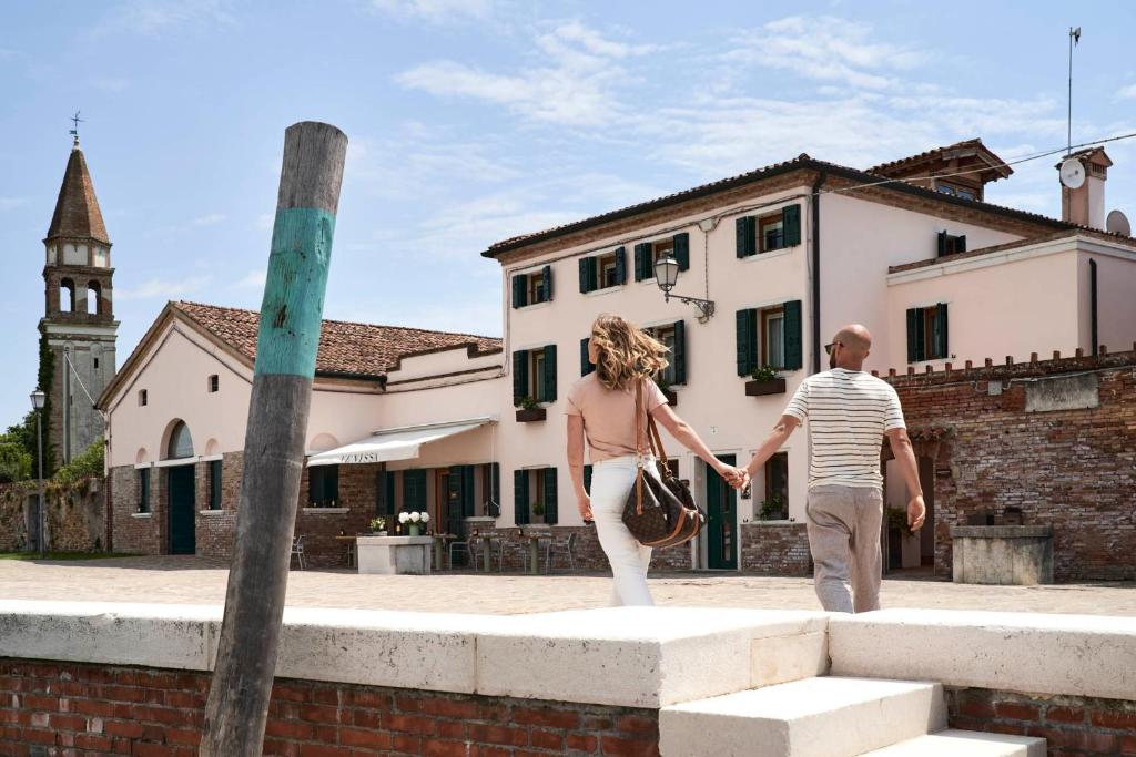 un hombre y una mujer caminando delante de un edificio en Venissa Wine Resort, en Burano