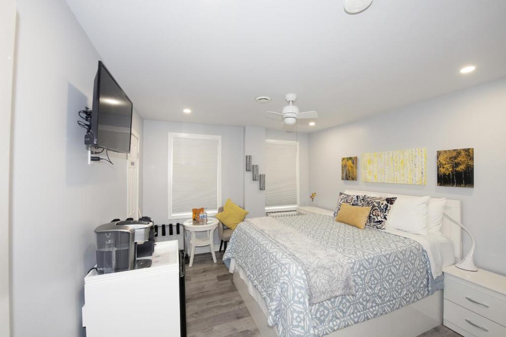 a white bedroom with a bed and a television at Serene Niagara Inn in Niagara Falls
