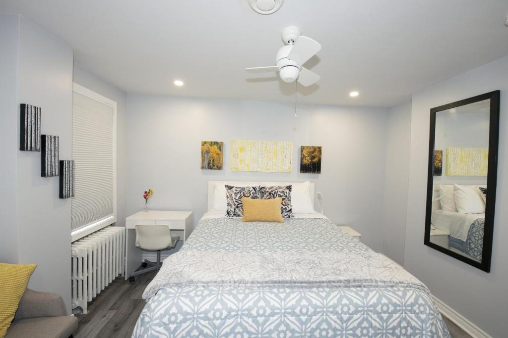 a white bedroom with a bed and a mirror at Serene Niagara Inn in Niagara Falls