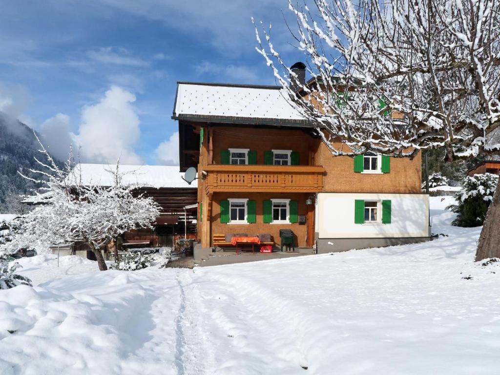 een houten huis in de sneeuw met een sneeuwbedekte tuin bij Holiday Home Haus Hermann - GOP225 by Interhome in Sankt Gallenkirch