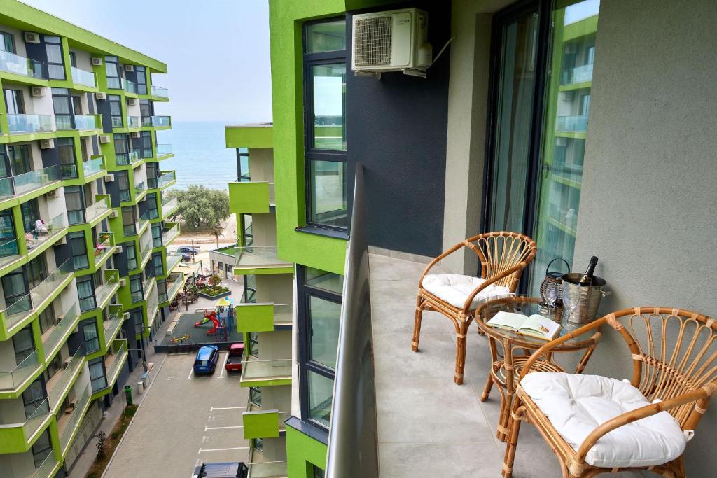 uma varanda com cadeiras e uma mesa num edifício em Opal Luxury Apartment 91 Spa n Pool Beach resort em Mamaia Nord – Năvodari