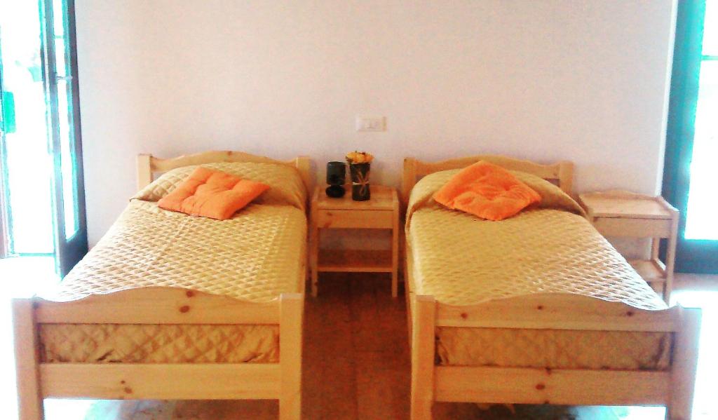 two beds with orange pillows on them in a room at Ostello Sociale Borgo Venno in Lavenone