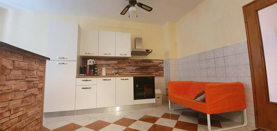a kitchen with white cabinets and an orange chair at Apartments New Charming in Senj
