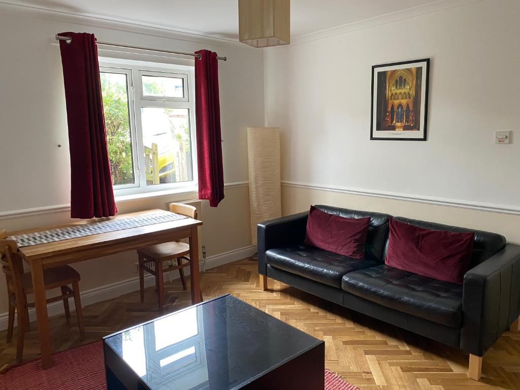 ein Wohnzimmer mit einem schwarzen Sofa und einem Tisch in der Unterkunft Byways Serviced Apartments in Salisbury