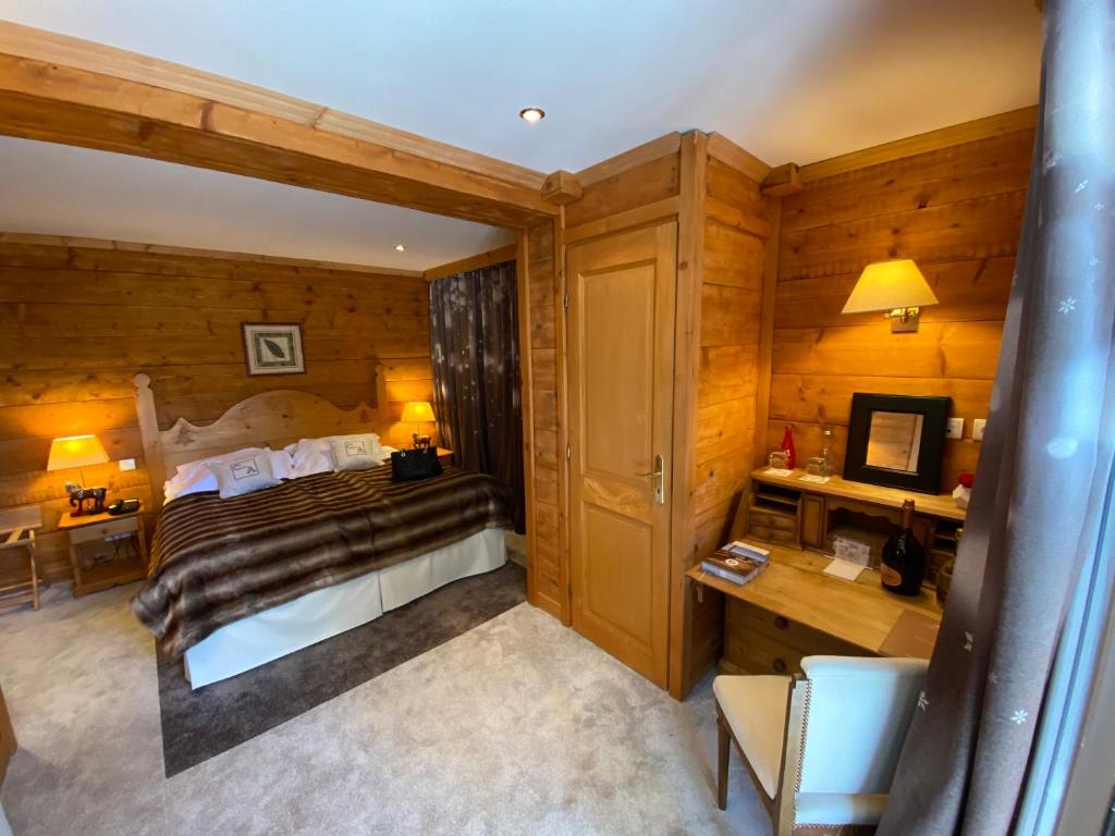 a bedroom with a bed and a desk with a television at Le Chalet d'Auron in Auron