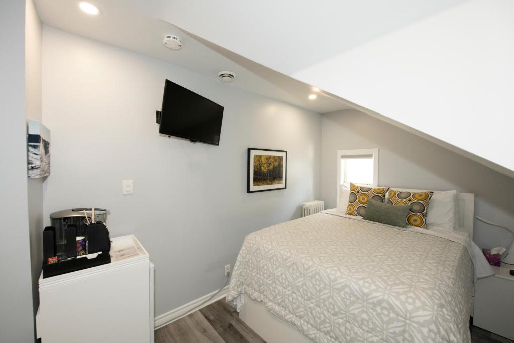 a bedroom with a bed and a tv on the wall at Serene Niagara Inn in Niagara Falls