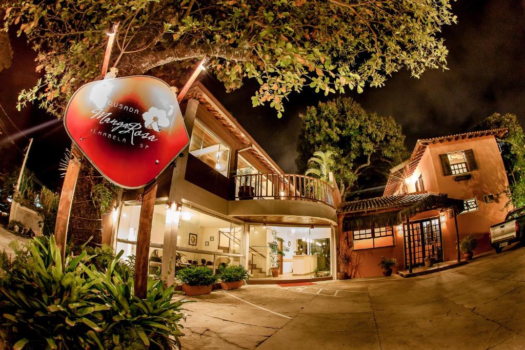 an apple sign in front of a house at night at Pousada Manga Rosa in Ilhabela