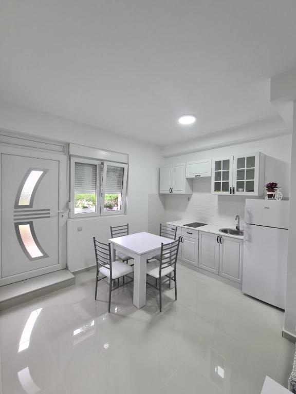 a white kitchen with a table and chairs in it at Apartmani Popivoda in Soko Banja