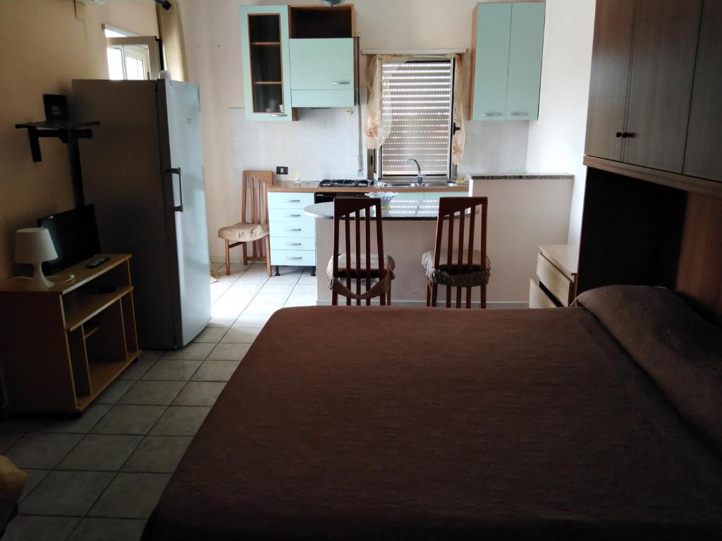 a small kitchen with two chairs and a refrigerator at casa vacanze di Genova Damiano in Schiavonea