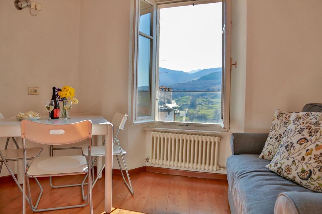 een woonkamer met een bank, een tafel en een raam bij Contempora Apartments - Ca' Brenta Attic in San Fedele Intelvi