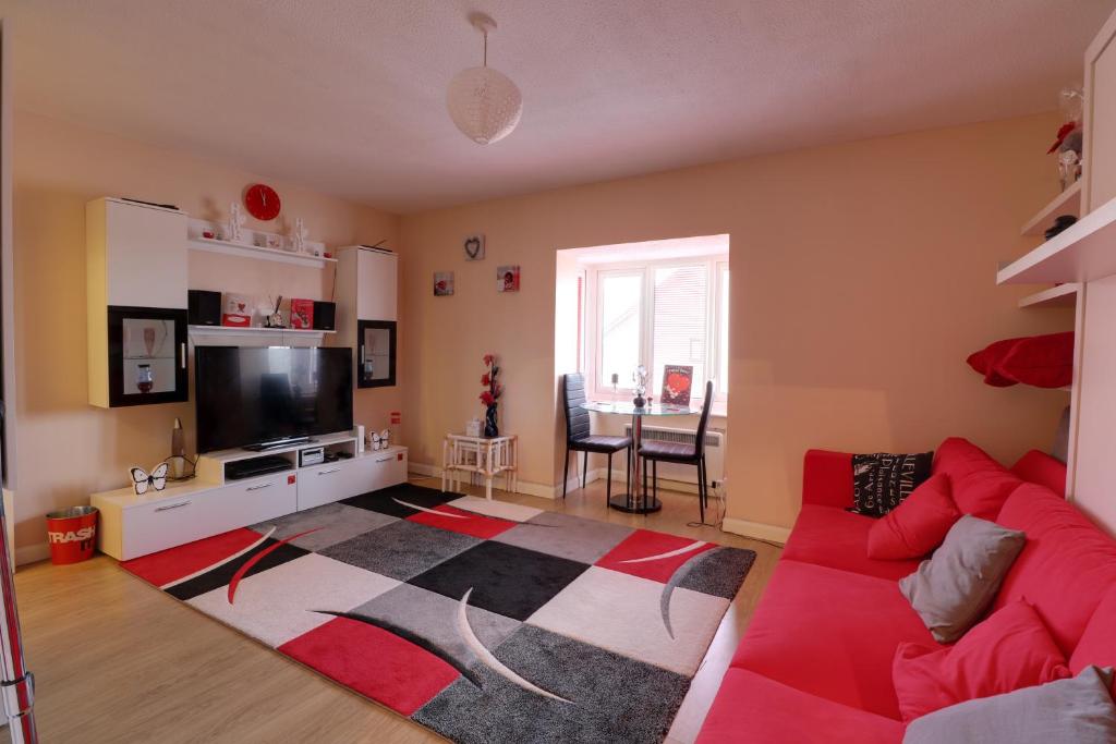 a living room with a red couch and a tv at Luxury Studio Apartment in Northolt