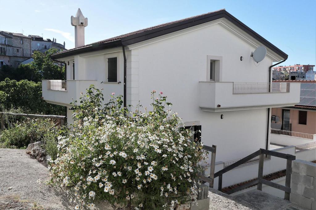 um edifício branco com uma cruz atrás de um arbusto em Nuovo appartamento San Marco em Vico del Gargano