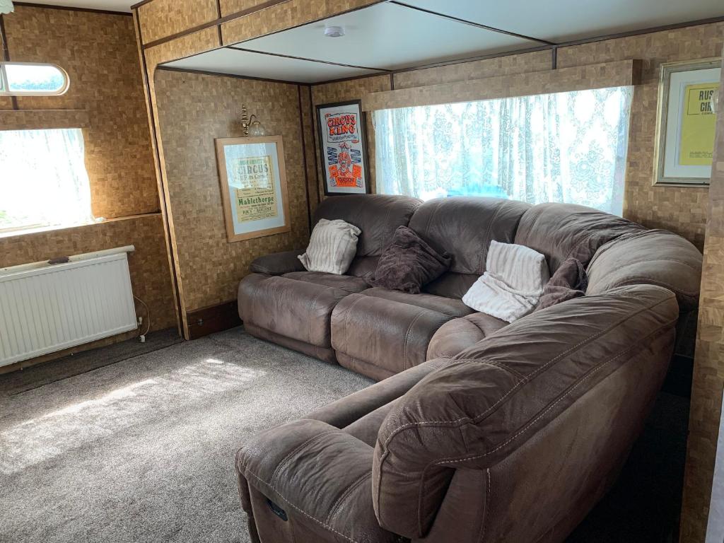 a living room with a large brown couch in a room at Vintage, Circus Holiday Home in Mablethorpe