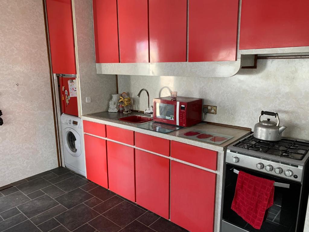 a red kitchen with a stove and a microwave at Vintage, Circus Holiday Home in Mablethorpe