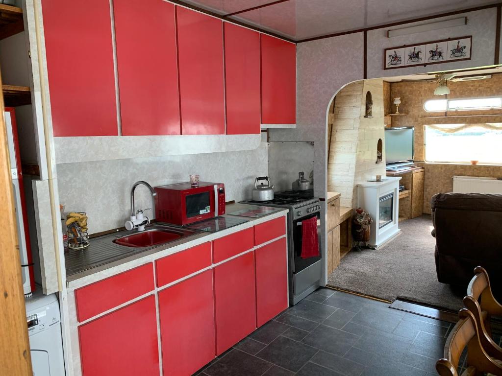 a kitchen with red cabinets and a red microwave at Vintage, Circus Holiday Home in Mablethorpe