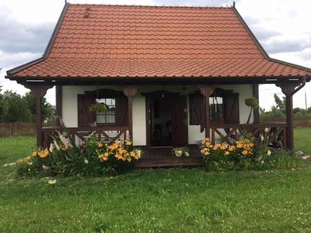 una pequeña casa con techo rojo y algunas flores en Domek całoroczny na Kaszubach "Kołowrót", en Dziemiany