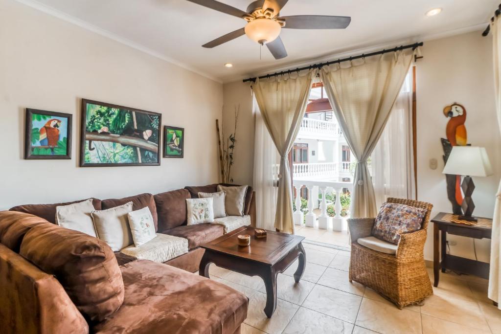 a living room with a couch and a ceiling fan at La Paloma Blanca in Jacó