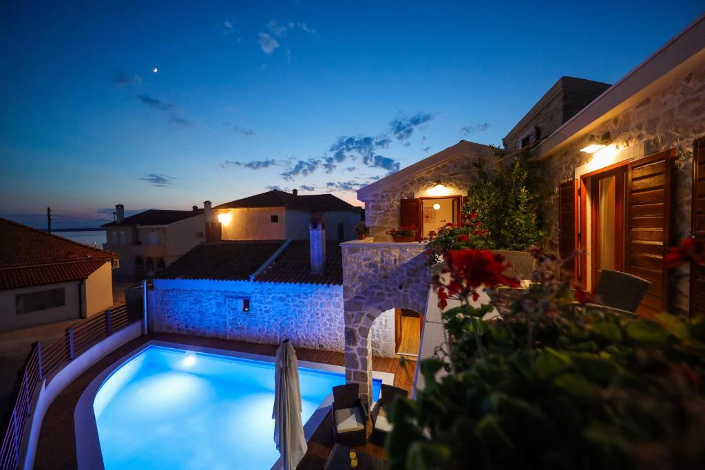 a swimming pool in front of a house at night at Villa Toka in Petrcane