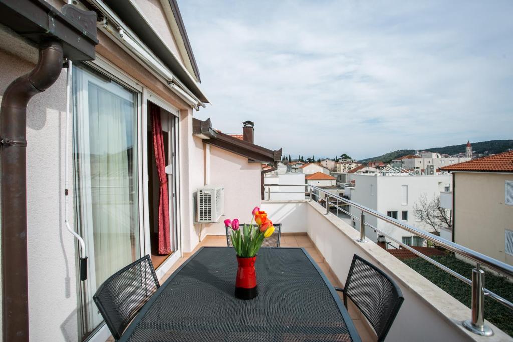 - un balcon avec une table et des fleurs dans l'établissement Apartments Bili, à Trogir