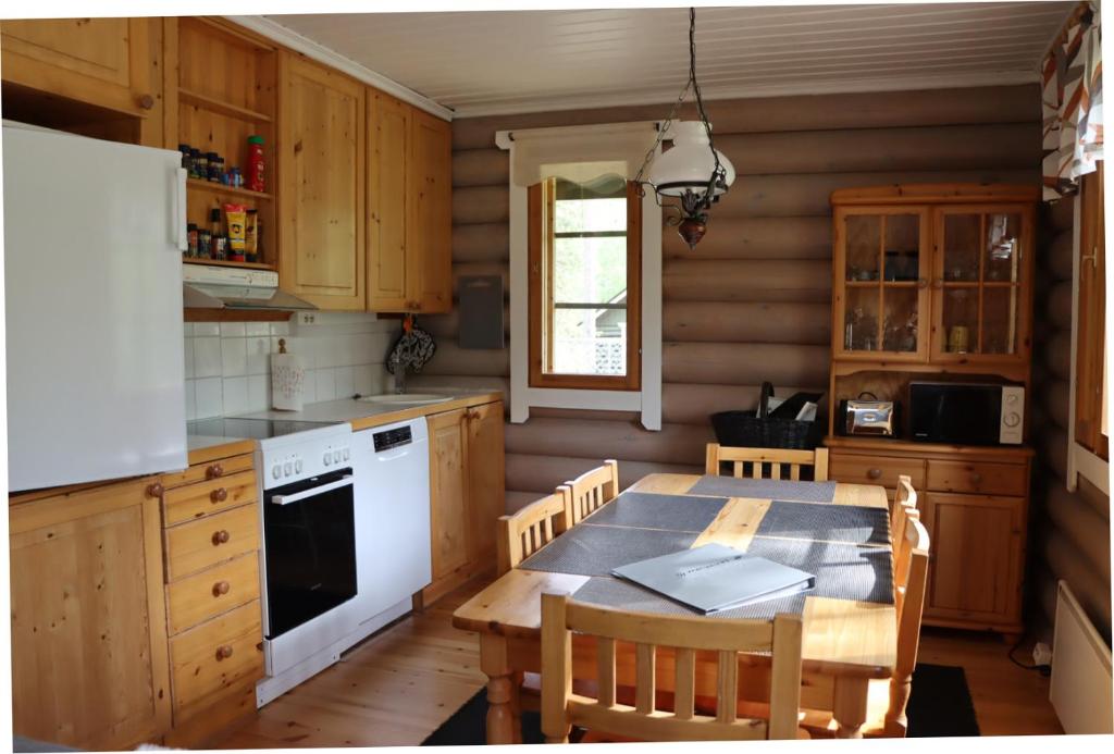 uma cozinha com uma mesa e um frigorífico branco em Levihaukka 10 em Sirkka