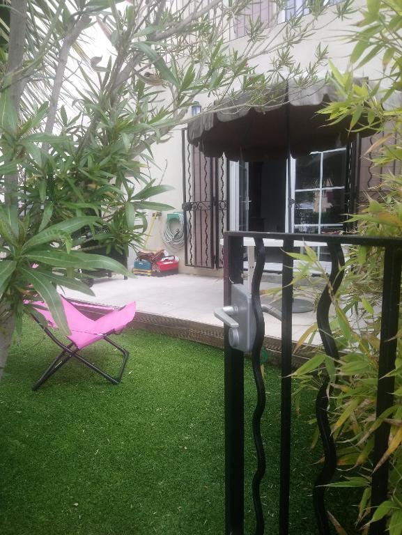 une chaise rose et une table dans une cour dans l'établissement Marina à Aigues Mortes - GARD, à Aigues-Mortes