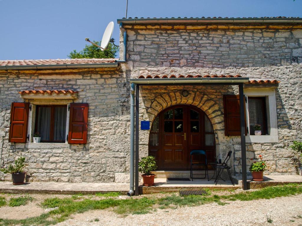 una casa in pietra con una porta in legno e una finestra di Apartments Heraki a Sveti Lovreč Pazenatički