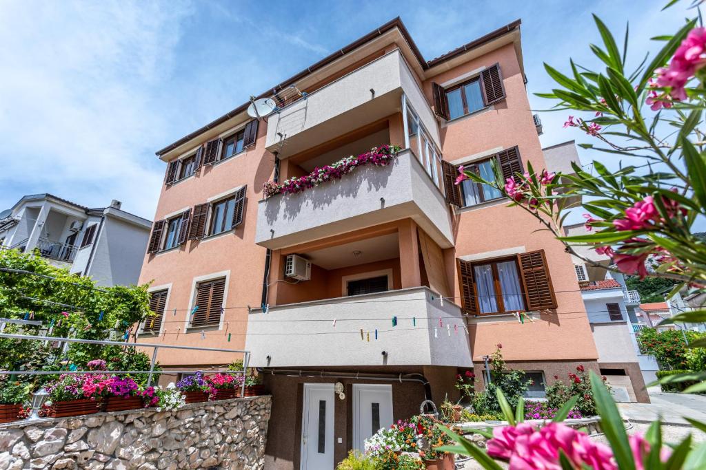 a pink building with flowers in front of it at Santima Apartments in Baška