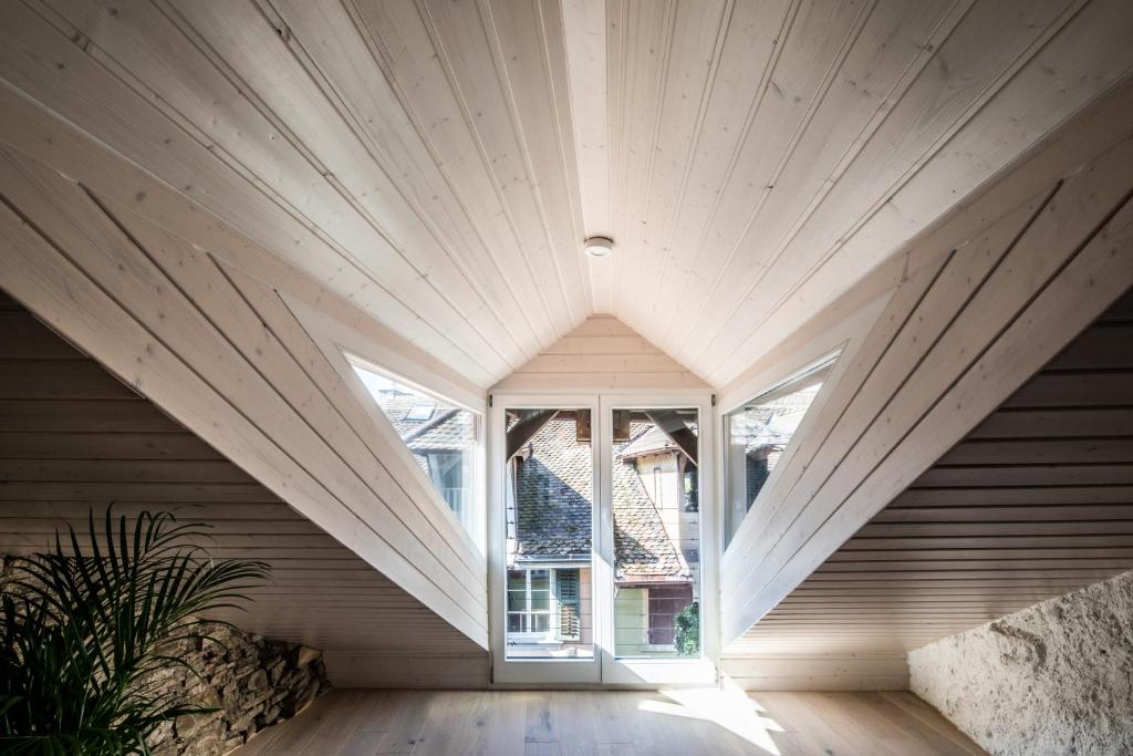 an attic room with a large window in a house at Duplex Allegro in La Neuveville