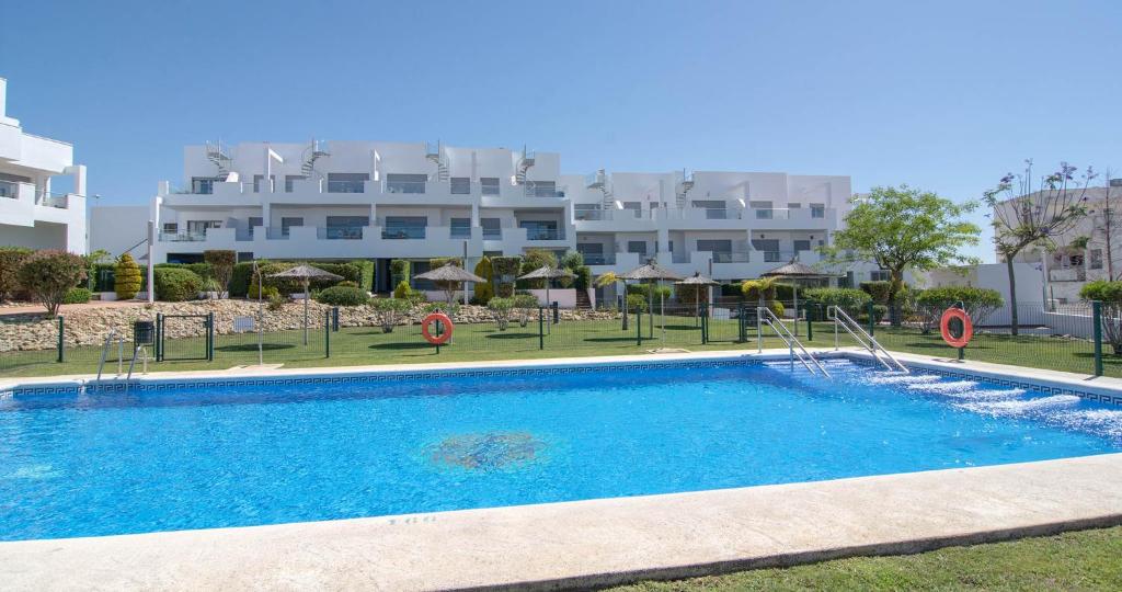 a swimming pool in front of a large building at Apartamentos Conil Park in Conil de la Frontera