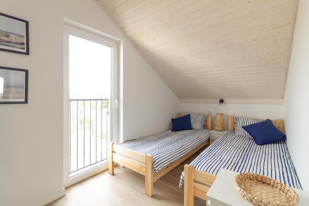 MorzeZatoka - apartamenty Władysławowo في فواديسوافوفو: سريرين في غرفة بها نافذة