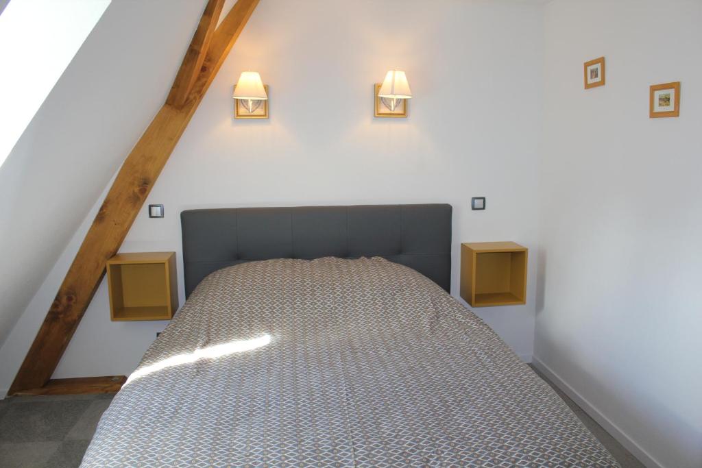a bed in a room with two lights on the wall at Gîte Le Cep d&#39;Or Alsace in Saint-Hippolyte