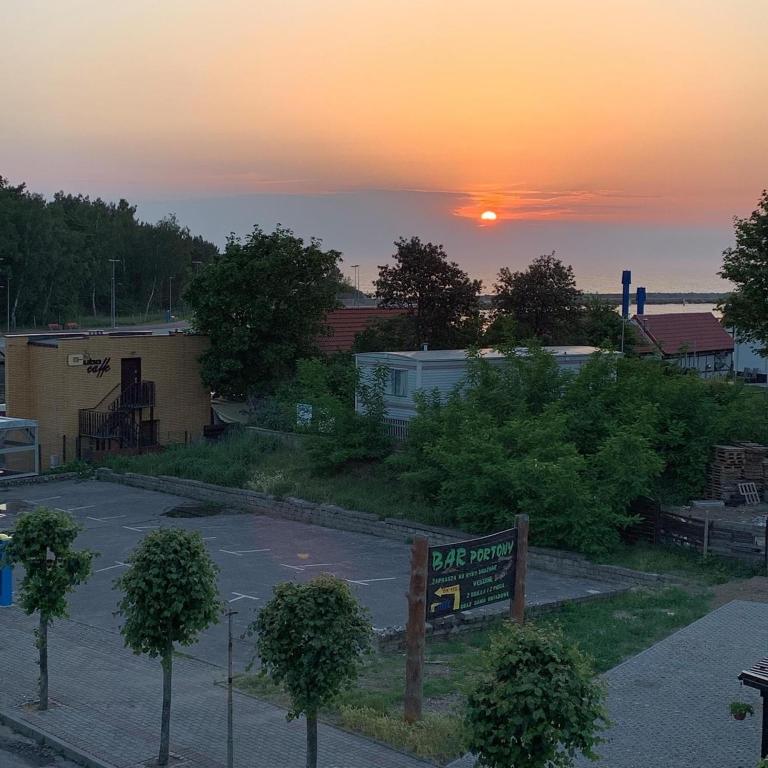 a parking lot with the sunset in the background at Dom Wczasowy PORTOWA PRZYSTAŃ 150m od plaży in Mrzeżyno