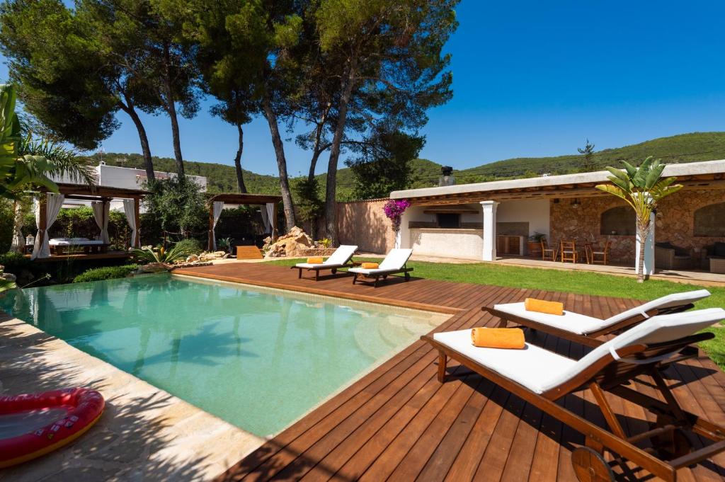 una piscina con terraza y sillas y una casa en Casa Es Pins en Santa Eulalia del Río