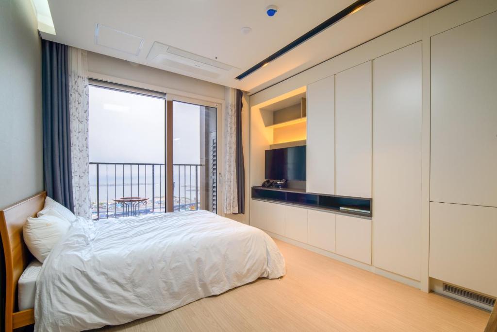 um quarto com uma cama e uma grande janela em Sokcho Daemyung Pension Samsung Home prestige em Sokcho