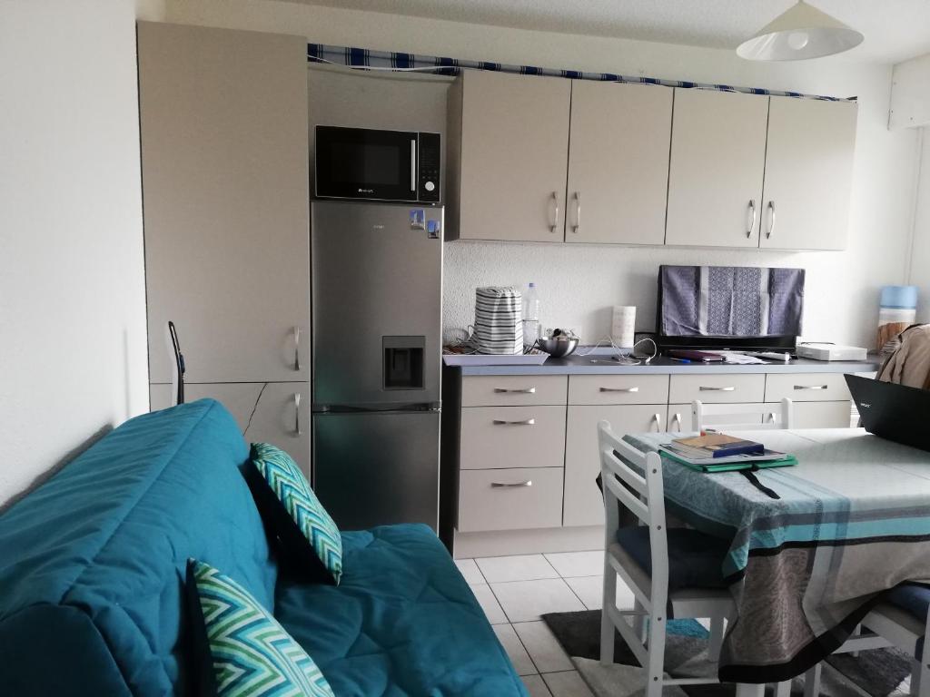 - une cuisine avec des placards blancs, une table et un réfrigérateur dans l'établissement Appartement 2 min à pied de la mer et du centre ville, à Saint-Georges-de-Didonne