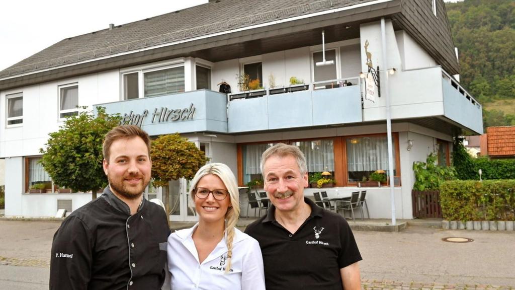 Dois homens e uma mulher em frente a uma casa. em Hotel Restaurant Hirsch em Schmiechen