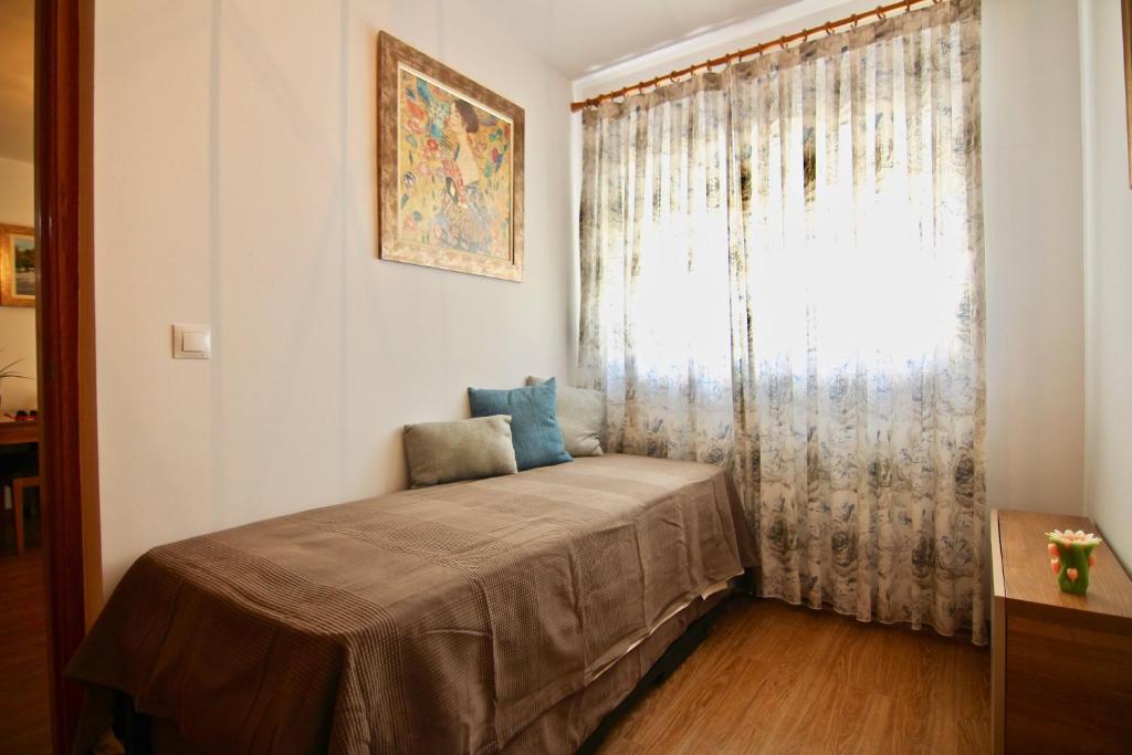 sypialnia z łóżkiem i oknem z zasłoną w obiekcie Apartamento CONFORTABLE junto al Mercado w Kadyksie