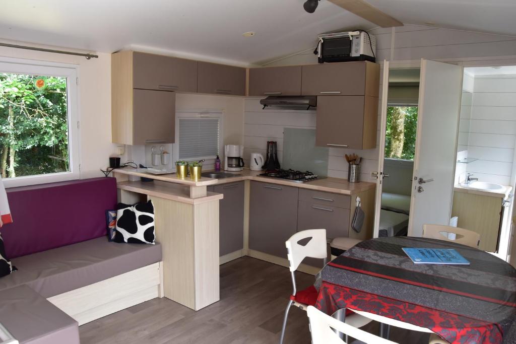eine kleine Küche und ein Esszimmer mit einem Tisch in der Unterkunft mobil-home sur 2000 mètres carrées in Le Faou