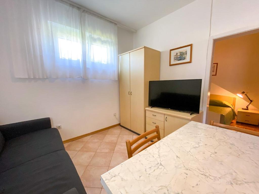 een woonkamer met een tafel, een tv en een bank bij Apartment Mandica in Savudrija