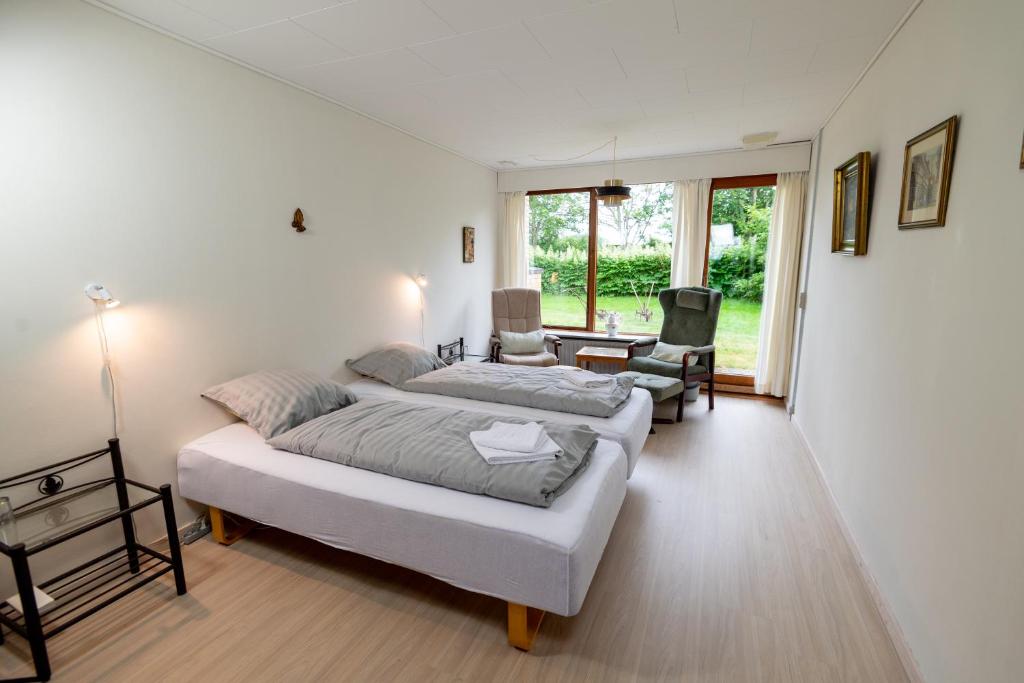 duża sypialnia z 2 łóżkami i krzesłem w obiekcie Shalom w mieście Gjerlev