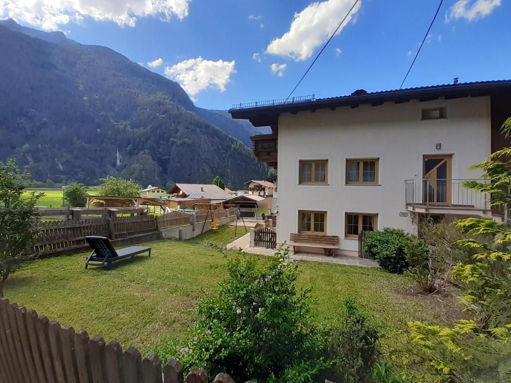 une maison blanche avec une clôture et des montagnes en arrière-plan dans l'établissement Ferienhaus Gerold Grießer, à Umhausen